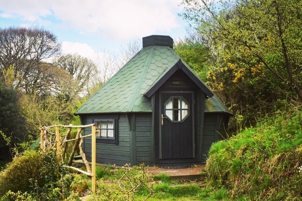 Green hobbit hut amongst the trees at Acorn Camping in Cornwall