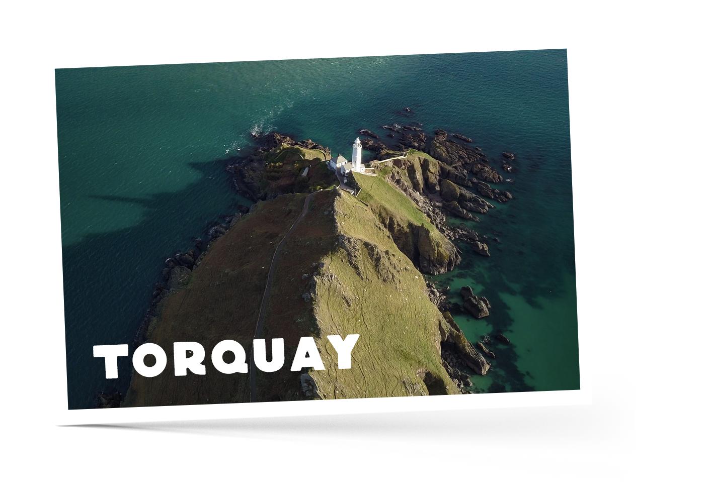 Birdseye view of rocky cliff in Torquay, Devon surrounded by loose rocks and sea with a lighthouse in at the bottom